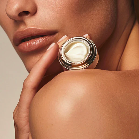 Woman holding a small jar of cream beside glowing skin