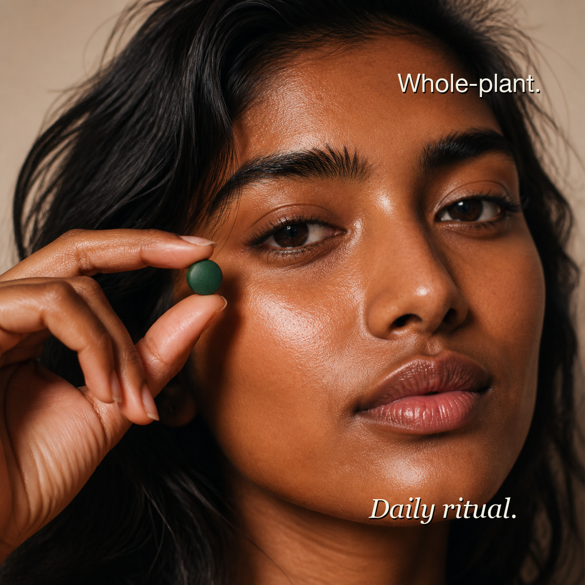 Woman holding a spirulina tablet — whole-plant daily ritual